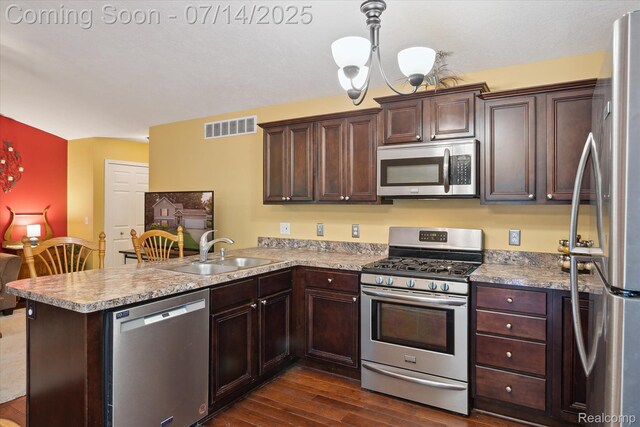 9481 Common Trl, Pinckney, MI 48169 - kitchen with stainless steel appliances, dark wood-type flooring, a peninsula, dark brown cabinetry, and light countertops
