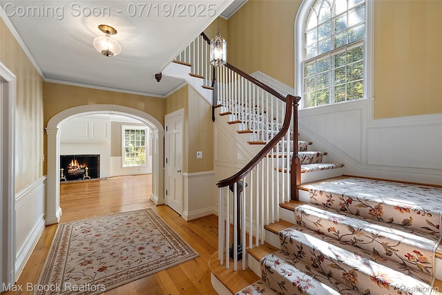 748 Waddington St, Bloomfield Hills, MI 48301 - stairway with wood-type flooring, a decorative wall, wainscoting, ornamental molding, and a lit fireplace
