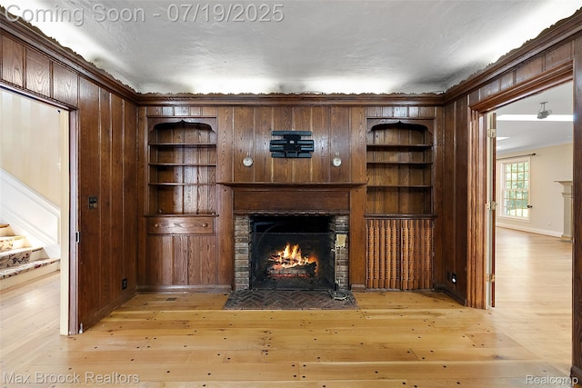 748 Waddington St, Bloomfield Hills, MI 48301 - unfurnished living room featuring a brick fireplace, wooden walls, light wood-style floors, built in features, and ornamental molding