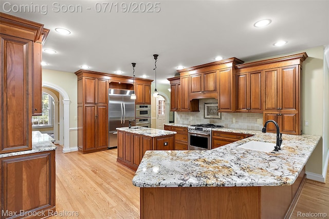 748 Waddington St, Bloomfield Hills, MI 48301 - kitchen with high quality appliances, arched walkways, a peninsula, brown cabinetry, and recessed lighting