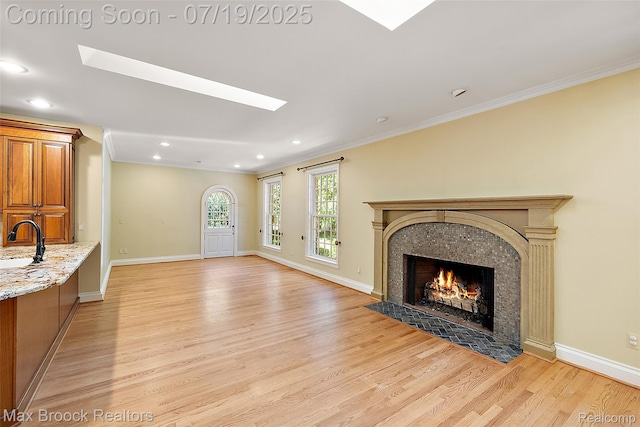 748 Waddington St, Bloomfield Hills, MI 48301 - unfurnished living room with light wood-style flooring, a skylight, a tiled fireplace, crown molding, and recessed lighting