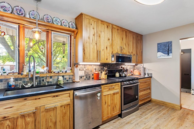916 Hillcrest Dr, Adrian, MI 49221 - kitchen with appliances with stainless steel finishes, tasteful backsplash, dark countertops, light wood-style flooring, and pendant lighting