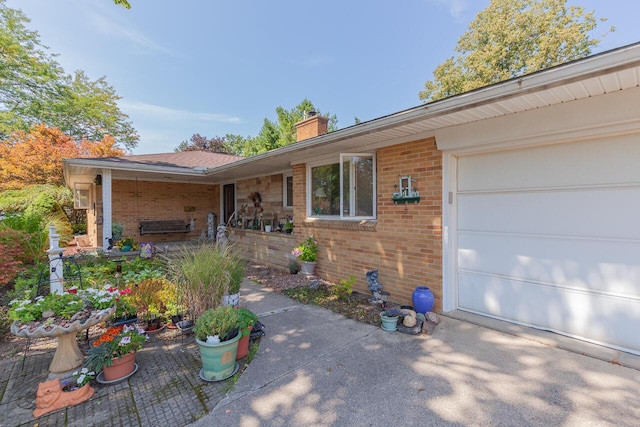 916 Hillcrest Dr, Adrian, MI 49221 - entrance to property with a chimney, brick siding, and an attached garage