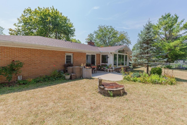 916 Hillcrest Dr, Adrian, MI 49221 - back of house featuring brick siding, a fire pit, a patio area, and a chimney