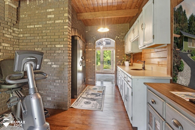 3078 Green Corners Rd, Lapeer, MI 48446 - kitchen with brick wall, light countertops, a wooden ceiling with exposed beams, wood finished floors, and white cabinetry