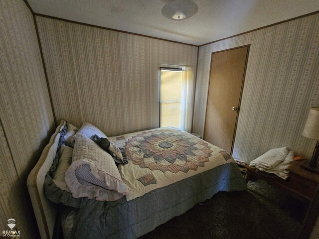 2789 Grass Lake Ave, Clare, MI 48632 - carpeted bedroom featuring crown molding, wallpapered walls, and a textured ceiling