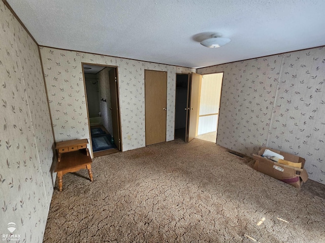 2789 Grass Lake Ave, Clare, MI 48632 - unfurnished bedroom featuring carpet floors, a textured ceiling, wallpapered walls, and multiple closets