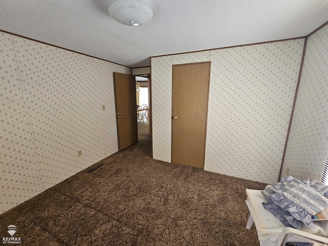 2789 Grass Lake Ave, Clare, MI 48632 - unfurnished bedroom with carpet, crown molding, a textured ceiling, and wallpapered walls