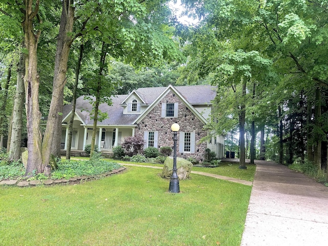 310 Sycamore St, Litchfield, MI 49252 - view of front of property with a front lawn, stone siding, a porch, concrete driveway, and a shingled roof
