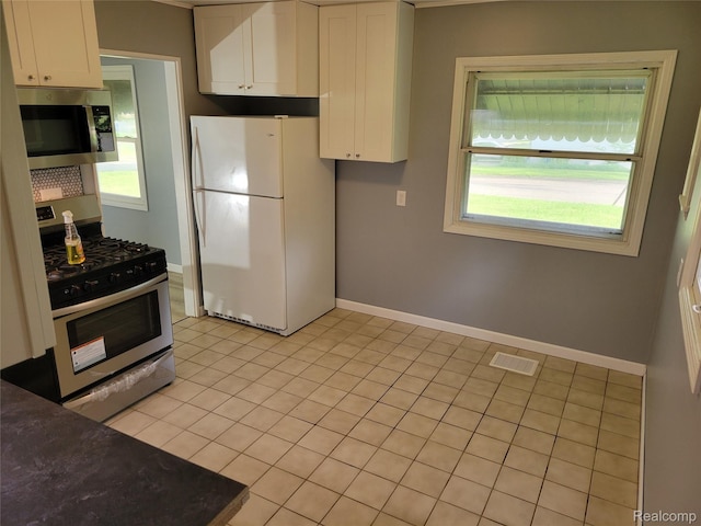 112 Darragh Dr, Battle Creek, MI 49015 - kitchen with appliances with stainless steel finishes, white cabinetry, dark countertops, and light tile patterned floors