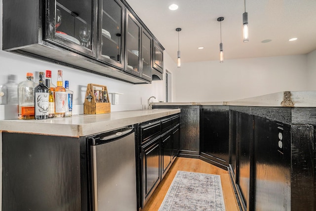 15518 Oak Ridge Dr, Spring Lake, MI 49456 - kitchen with dark cabinets, light wood-type flooring, fridge, decorative light fixtures, and glass insert cabinets