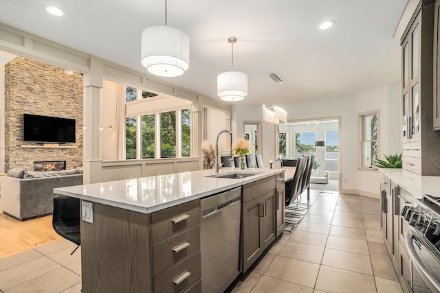 15518 Oak Ridge Dr, Spring Lake, MI 49456 - kitchen with stainless steel appliances, light tile patterned flooring, dark brown cabinetry, light countertops, and a center island with sink
