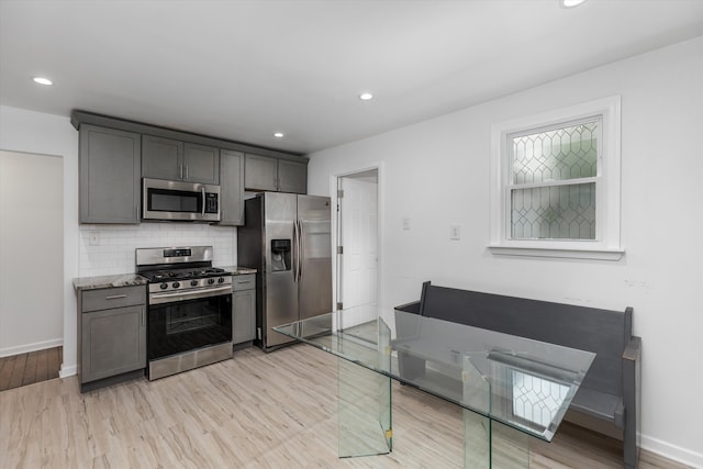 21560 Poinciana St, Southfield, MI 48033 - kitchen with appliances with stainless steel finishes, light wood-style flooring, tasteful backsplash, light stone counters, and recessed lighting