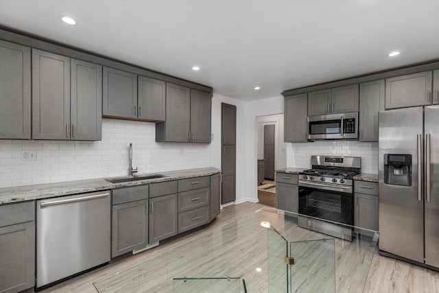 21560 Poinciana St, Southfield, MI 48033 - kitchen featuring appliances with stainless steel finishes, light stone countertops, decorative backsplash, recessed lighting, and light wood-style flooring