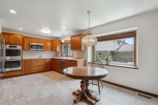 1726 Black Maple Dr, Rochester Hills, MI 48309 - kitchen featuring stainless steel appliances, plenty of natural light, tasteful backsplash, brown cabinetry, and recessed lighting