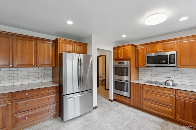 1726 Black Maple Dr, Rochester Hills, MI 48309 - kitchen featuring appliances with stainless steel finishes, brown cabinets, tasteful backsplash, light stone counters, and light tile patterned floors