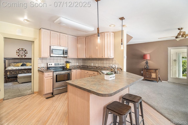 4420 Pinedale Ave, Clarkston, MI 48346 - kitchen featuring stainless steel appliances, light brown cabinetry, a kitchen bar, dark countertops, and a peninsula