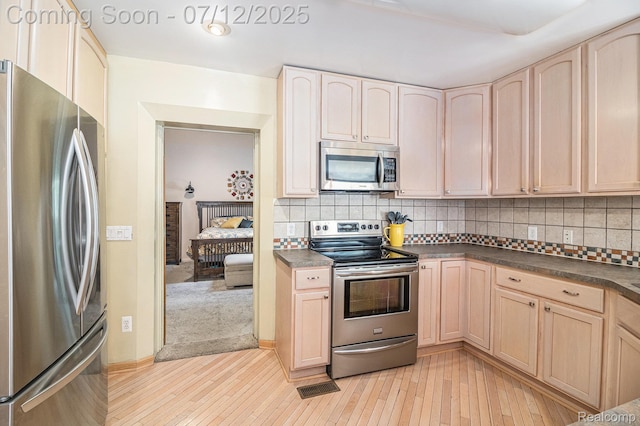 4420 Pinedale Ave, Clarkston, MI 48346 - kitchen with stainless steel appliances, dark countertops, light wood finished floors, backsplash, and light brown cabinetry