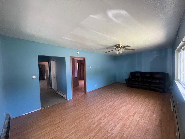 129 W Walnut St, Saint Charles, MI 48655 - unfurnished living room with a baseboard radiator, wood finished floors, ceiling fan, and a textured ceiling