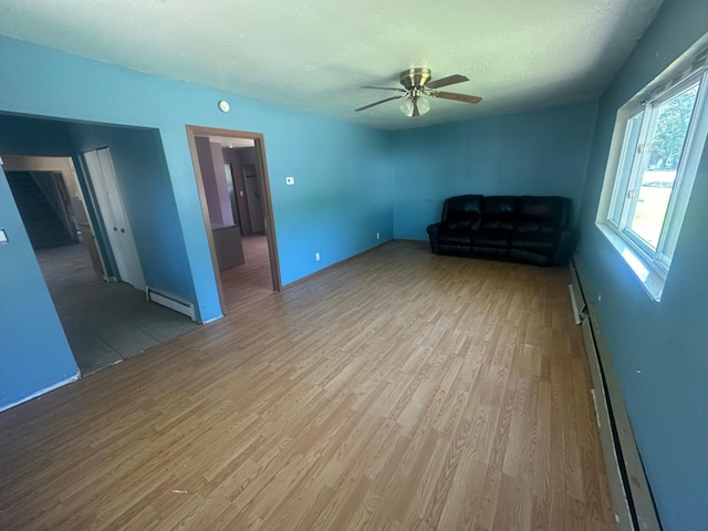 129 W Walnut St, Saint Charles, MI 48655 - unfurnished living room with a baseboard radiator, wood finished floors, ceiling fan, and a textured ceiling