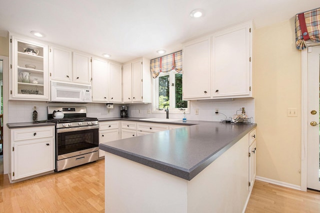1410 Rothbury Dr NE, Grand Rapids, MI 49505 - kitchen featuring white microwave, stainless steel gas range, dark countertops, light wood-style flooring, and recessed lighting