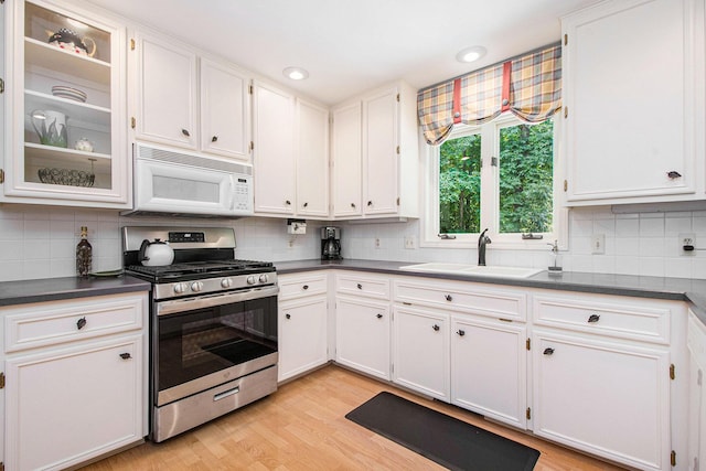 1410 Rothbury Dr NE, Grand Rapids, MI 49505 - kitchen with white microwave, gas stove, dark countertops, white cabinetry, and recessed lighting