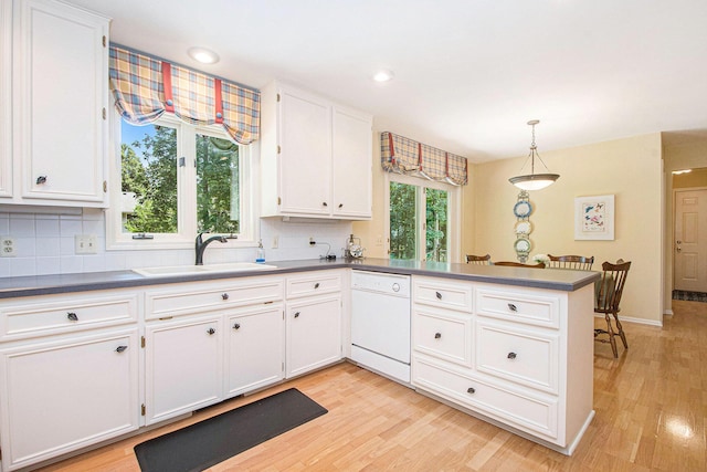1410 Rothbury Dr NE, Grand Rapids, MI 49505 - kitchen featuring white dishwasher, dark countertops, a peninsula, backsplash, and light wood-style flooring