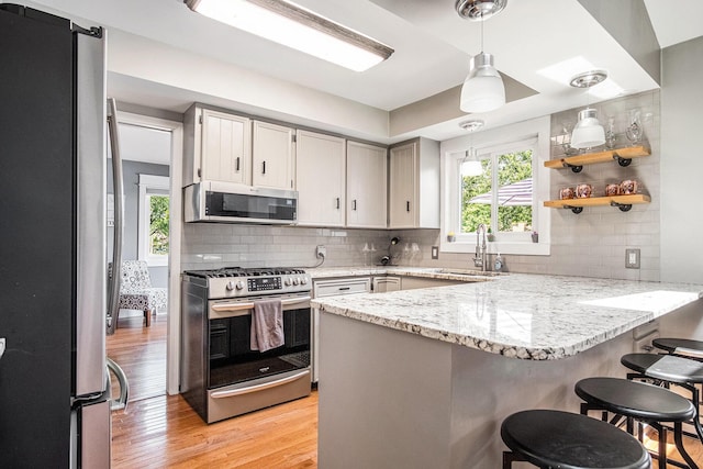 1836 Ridgewood Ave SE, Grand Rapids, MI 49506 - kitchen featuring appliances with stainless steel finishes, a peninsula, light wood-style flooring, and decorative backsplash