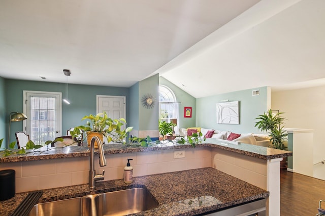 3197 Primrose Ln, Ypsilanti, MI 48197 - kitchen with open floor plan, dark stone countertops, dark wood-type flooring, vaulted ceiling, and pendant lighting
