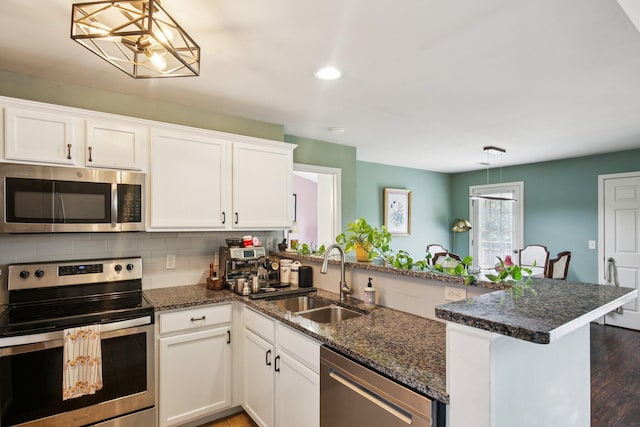 3197 Primrose Ln, Ypsilanti, MI 48197 - kitchen featuring appliances with stainless steel finishes, a peninsula, white cabinets, decorative backsplash, and recessed lighting