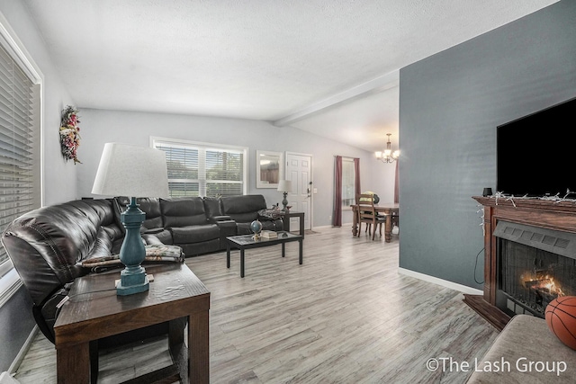 2851 18 Mile Rd, Kent City, MI 49330 - living room with light wood finished floors, a lit fireplace, a chandelier, and a textured ceiling