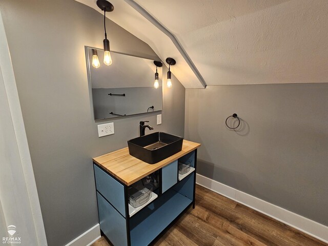 624 E Comstock St, Owosso, MI 48867 - bathroom featuring wood finished floors, vanity, vaulted ceiling, and a textured ceiling