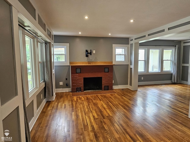 624 E Comstock St, Owosso, MI 48867 - unfurnished living room with wood finished floors, healthy amount of natural light, recessed lighting, and a brick fireplace