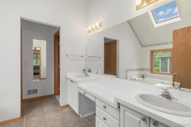6512 White Lake Rd, Clarkston, MI 48346 - bathroom featuring double vanity, a skylight, a tub with jets, and tile patterned flooring