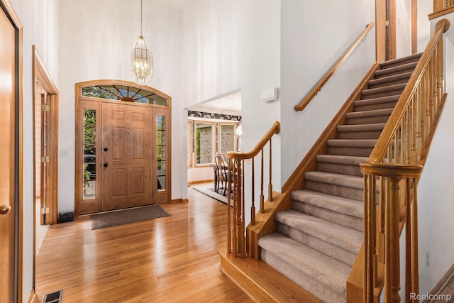 6512 White Lake Rd, Clarkston, MI 48346 - entryway featuring light wood finished floors, stairway, a towering ceiling, and a chandelier