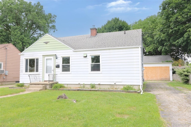 3922 Hogarth Ave, Flint, MI 48532 - view of front of house with a chimney, a front lawn, asphalt driveway, an outdoor structure, and roof with shingles