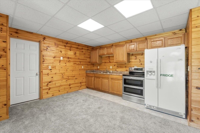 7350 N Territorial Rd, Dexter, MI 48130 - kitchen featuring white refrigerator with ice dispenser, range with two ovens, wooden walls, light carpet, and a drop ceiling