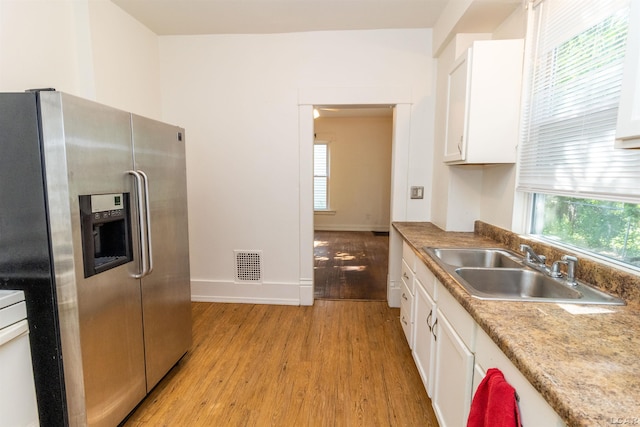 422 S Winter St, Adrian, MI 49221 - kitchen featuring stainless steel fridge, light wood-style floors, white cabinets, and healthy amount of natural light