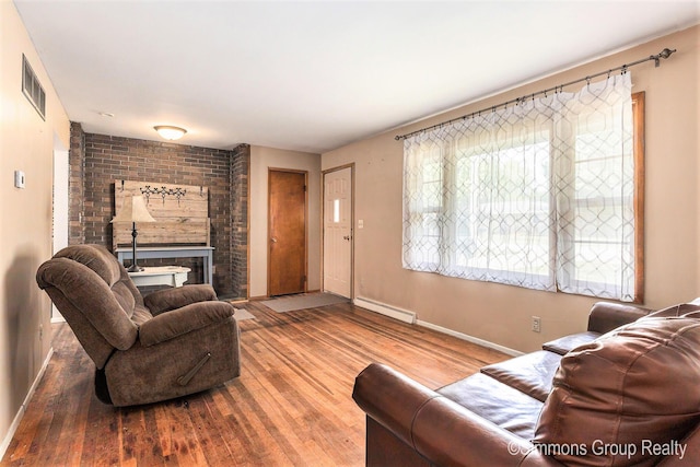 252 Jeffrey St, Cedar Springs, MI 49319 - living area with a brick fireplace, a baseboard heating unit, and wood finished floors