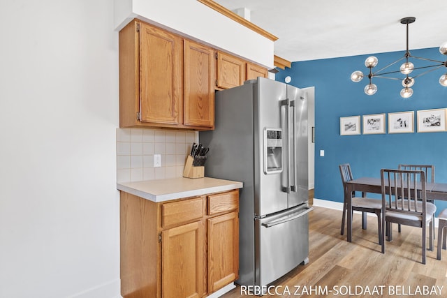 3520 Auburn Ave NE, Grand Rapids, MI 49525 - kitchen with stainless steel fridge, backsplash, light wood-style flooring, light countertops, and a chandelier