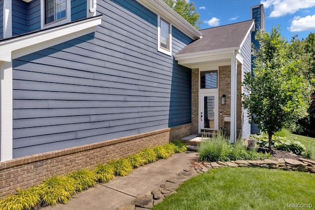 5612 Northcrest Xing, Clarkston, MI 48346 - view of exterior entry featuring brick siding and a chimney
