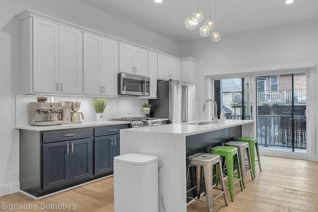 2037 11th St Unit 3, Detroit, MI 48216 - kitchen with stainless steel appliances, backsplash, light wood-type flooring, light countertops, and a center island with sink
