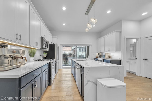 2037 11th St Unit 3, Detroit, MI 48216 - kitchen featuring appliances with stainless steel finishes, light wood finished floors, a kitchen island with sink, recessed lighting, and pendant lighting