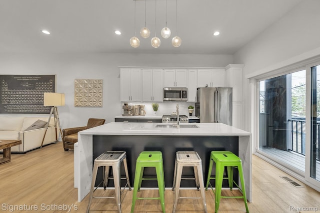 2037 11th St Unit 3, Detroit, MI 48216 - kitchen with stainless steel appliances, light countertops, a kitchen breakfast bar, and light wood-style floors