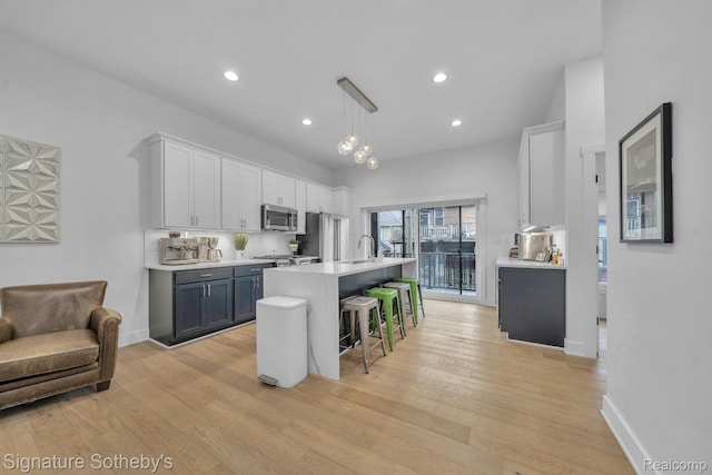 2037 11th St Unit 3, Detroit, MI 48216 - kitchen featuring stainless steel appliances, light countertops, a breakfast bar, light wood-style flooring, and an island with sink