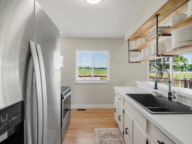 1140 Wing Dr, Ann Arbor, MI 48103 - kitchen with stainless steel appliances, open shelves, light wood-style flooring, white cabinetry, and light countertops