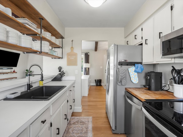 1140 Wing Dr, Ann Arbor, MI 48103 - kitchen featuring appliances with stainless steel finishes, light wood-style flooring, white cabinetry, open shelves, and butcher block counters