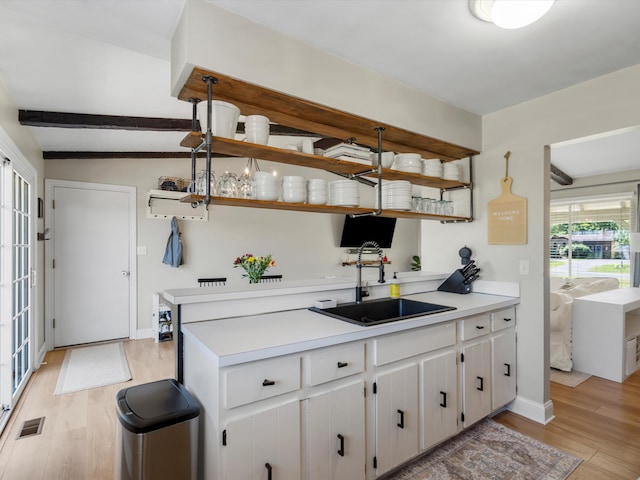 1140 Wing Dr, Ann Arbor, MI 48103 - kitchen with open shelves, light wood finished floors, light countertops, white cabinetry, and a peninsula