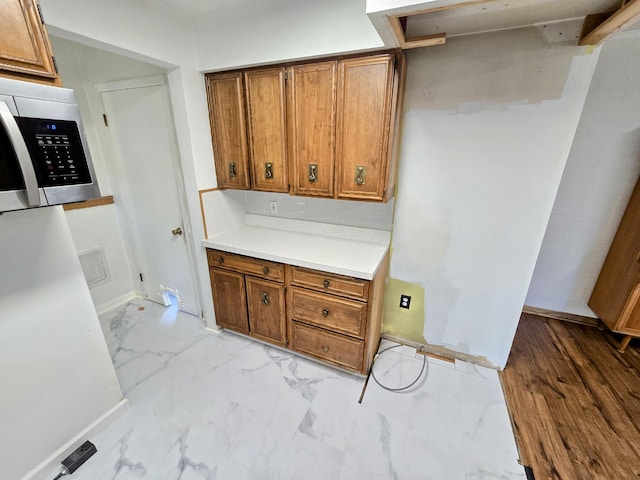 27751 Palomino Ave, Warren, MI 48093 - kitchen featuring stainless steel microwave, brown cabinetry, light marble finish floors, and light countertops
