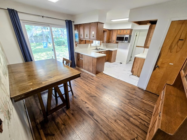 27751 Palomino Ave, Warren, MI 48093 - kitchen featuring brown cabinets, stainless steel microwave, light countertops, a peninsula, and light wood finished floors
